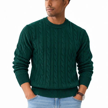 Heren kabeltrui met ronde hals, lange mouwen en klassiek kabelgebreid patroon, gedragen door een mannelijk model met een witte pantalon tegen een witte achtergrond.