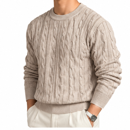 Heren kabeltrui met ronde hals, lange mouwen en klassiek kabelgebreid patroon, gedragen door een mannelijk model met een witte pantalon tegen een witte achtergrond.