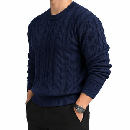 Heren kabeltrui met ronde hals, lange mouwen en klassiek kabelgebreid patroon, gedragen door een mannelijk model met een witte pantalon tegen een witte achtergrond.