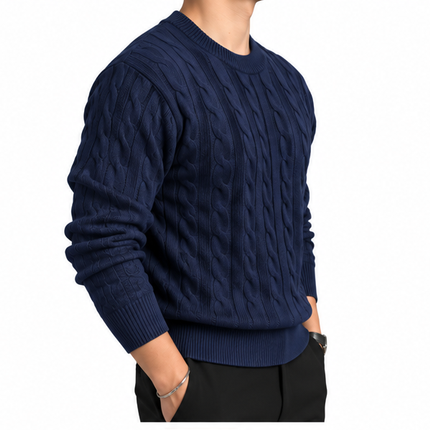 Heren kabeltrui met ronde hals, lange mouwen en klassiek kabelgebreid patroon, gedragen door een mannelijk model met een witte pantalon tegen een witte achtergrond.