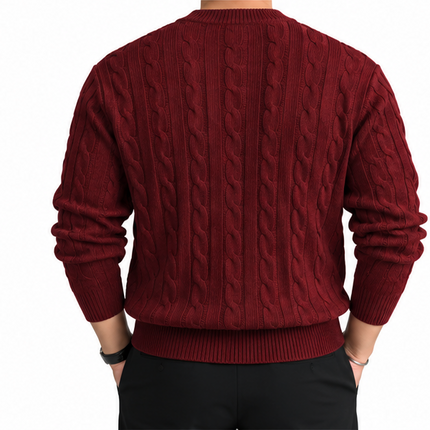 heren kabeltrui met ronde hals, lange mouwen en klassiek kabelgebreid patroon, gedragen door een mannelijk model met een witte pantalon tegen een witte achtergrond.