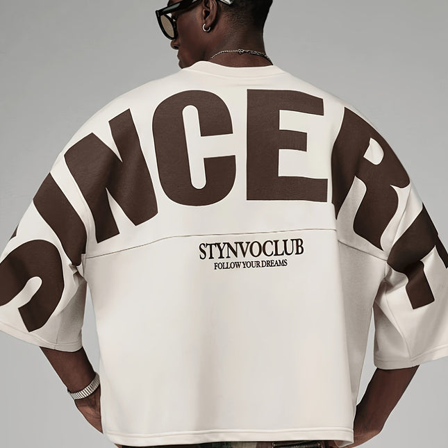 Oversized heren T-shirt in khaki, voorkant met zwarte STYNVOCLUB-letterprint, ronde hals, verlaagde schouders en grafische mouwprint op witte achtergrond.