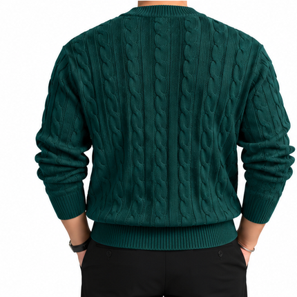 Heren kabeltrui met ronde hals, lange mouwen en klassiek kabelgebreid patroon, gedragen door een mannelijk model met een witte pantalon tegen een witte achtergrond.