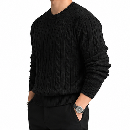 Heren kabeltrui met ronde hals, lange mouwen en klassiek kabelgebreid patroon, gedragen door een mannelijk model met een witte pantalon tegen een witte achtergrond.